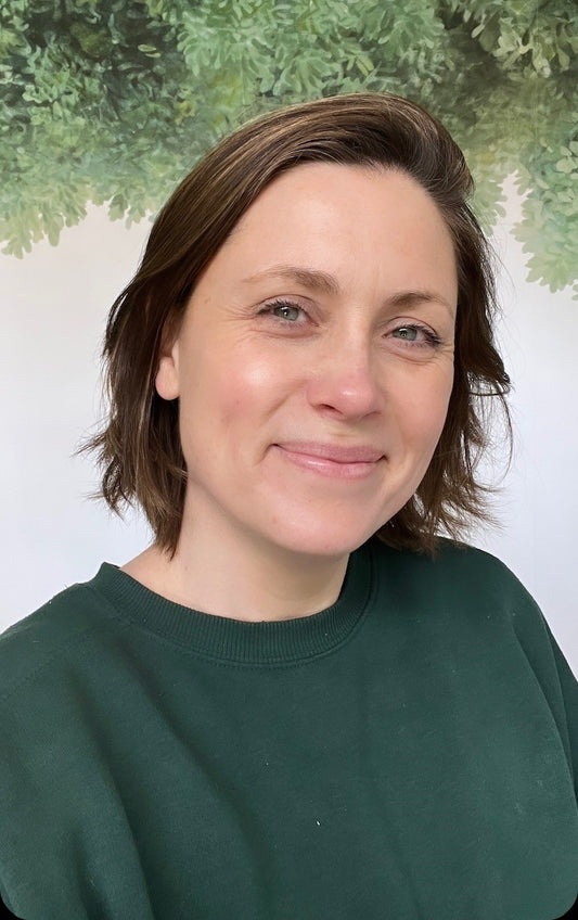 Louise smiling in front of tree mural