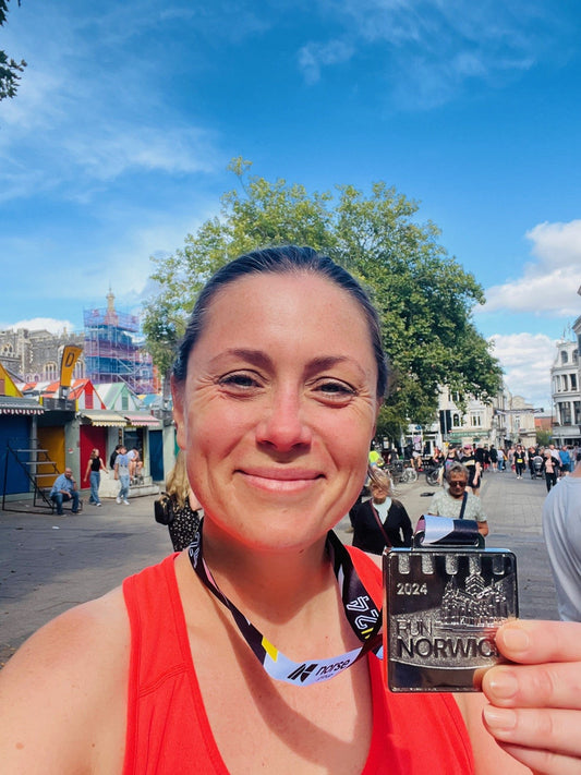 Louise Thompson smiling holding a Norwich 10km race medal